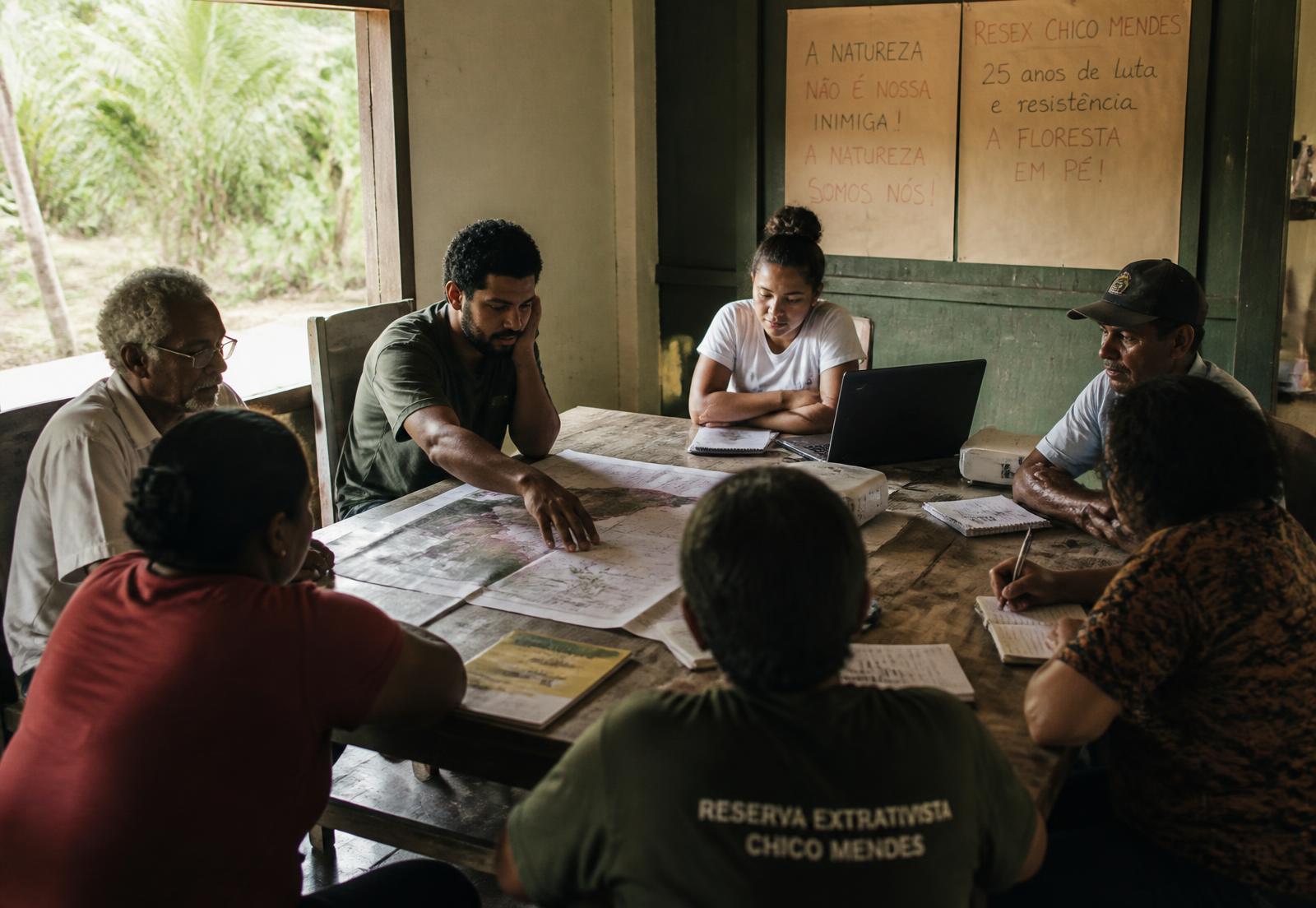 Reunião de organização comunitária em torno de mapas impressos, em sede rural